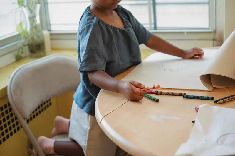 Young child coloring with crayons at a table during after school time