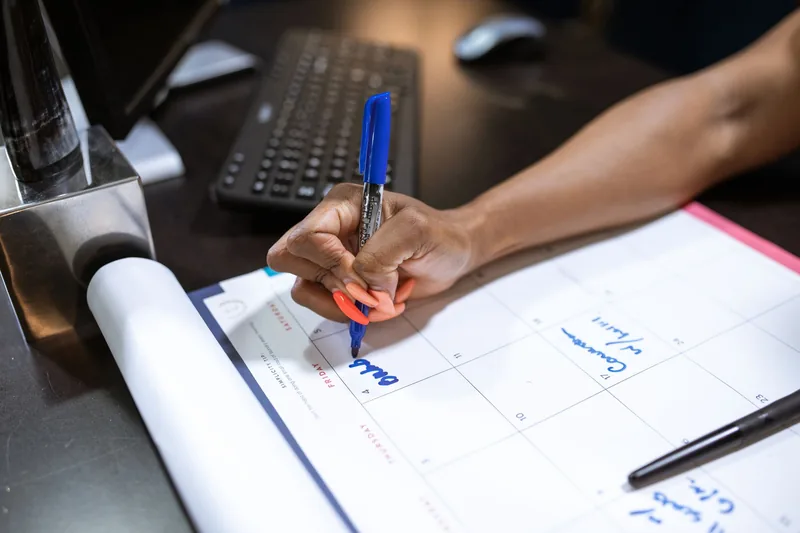 Parent marking a calendar to plan before and after school care around school breaks