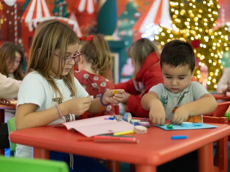 Children making holiday crafts at a table during a holiday camp for kids