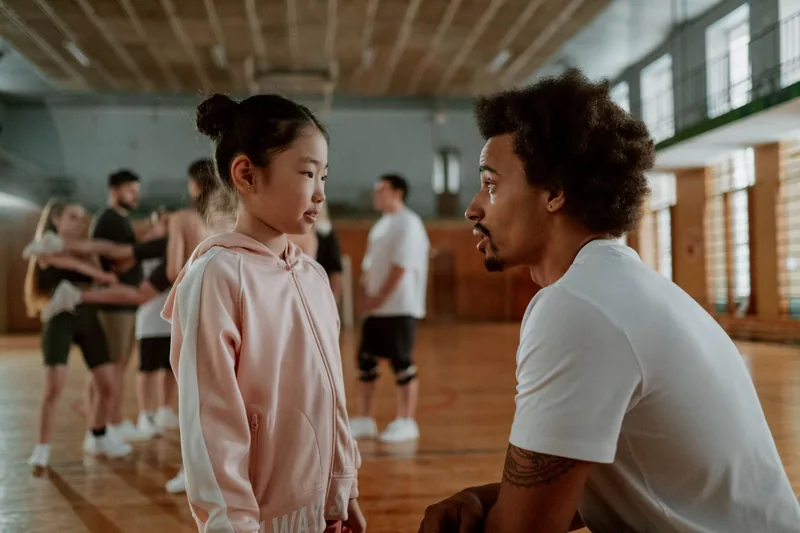 Coach giving one-on-one instruction to a young student during a PE class