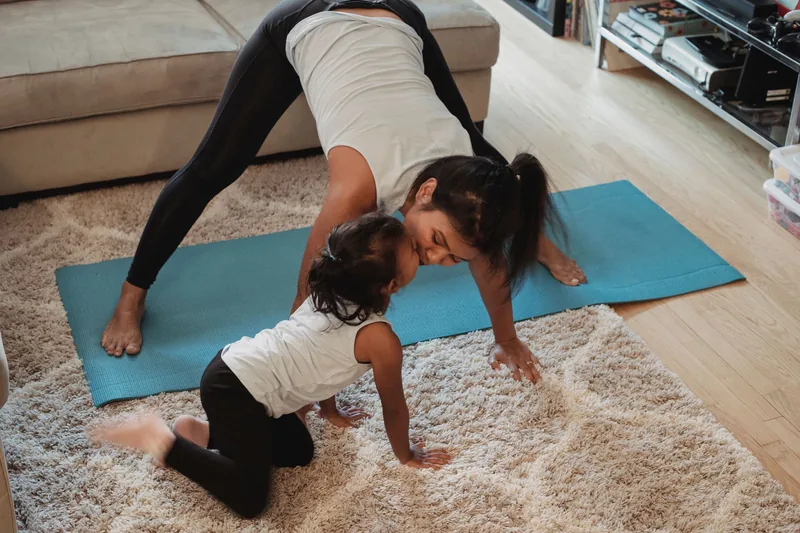 Mother and young daughter exercising together on a yoga mat at home