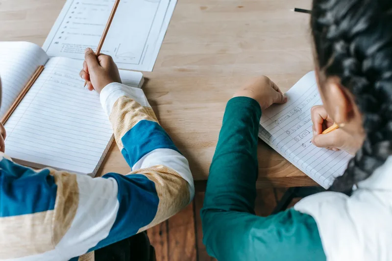 Two children doing homework together at a table in an after school program