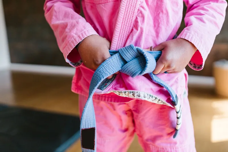 Child tying a colored martial arts belt before class