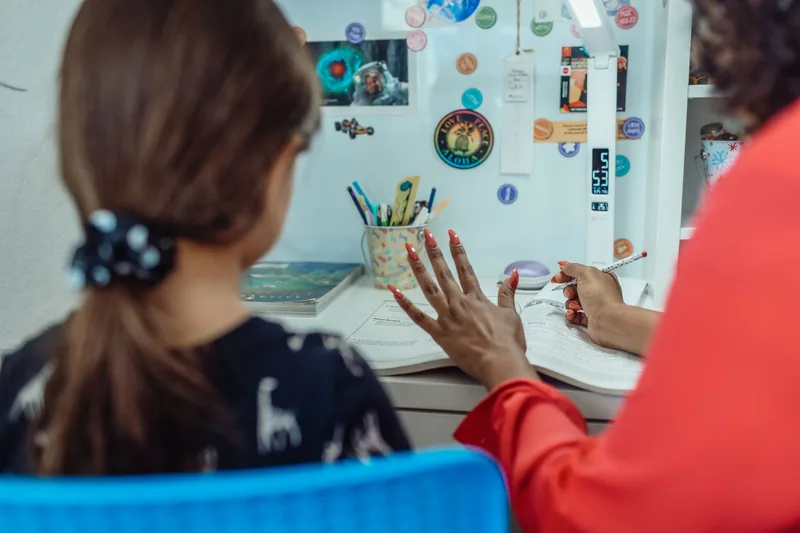 Mother helping her daughter with a homeschool lesson at a desk at home